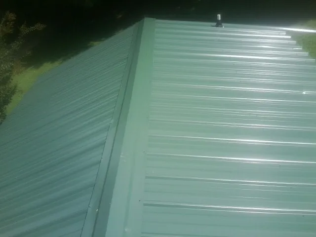 New green metal panels meeting at the ridge of a roof — Flat Roof Repair work by our crew in Pipersville