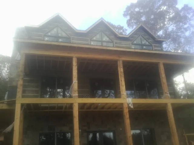 Dormers and porch framing on a large log home under construction — Roof Coating work by our crew in Pipersville