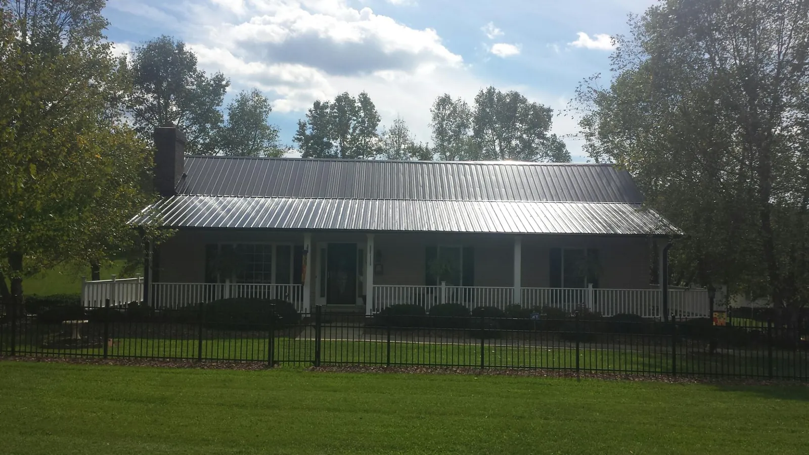 Gray metal roof on a brick ranch with a full width front porch — Gutter Guard Installation work by our crew in Pipersville