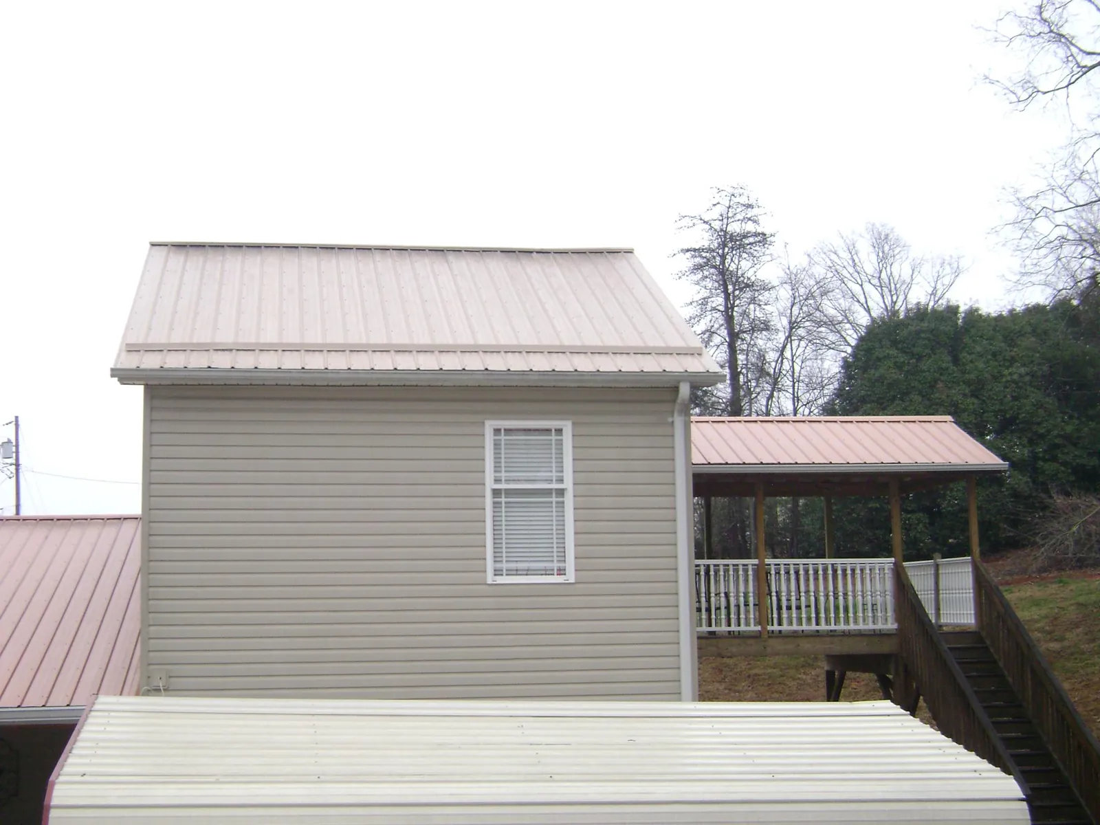 Tan metal roofs on a two story addition and attached porch, from a Roof Replacement job in Pipersville