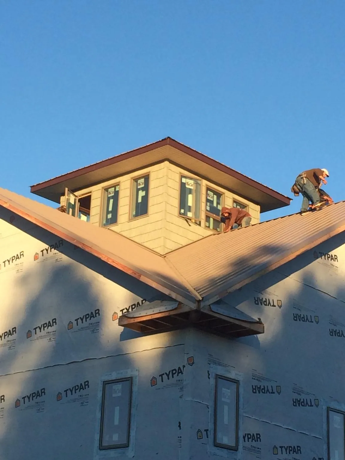 Roofers working around a rooftop cupola on a new metal roof at sunset — Roof Waterproofing in Pipersville by Roofing Brothers